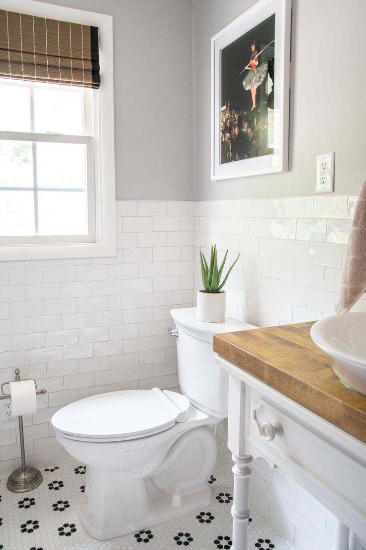 a white toilet sitting next to a sink in a bathroom under a window with blinds