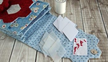 sewing supplies laid out on a wooden floor next to some thread and paper items that include scissors