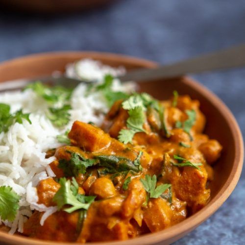 a brown bowl filled with rice and chicken curry