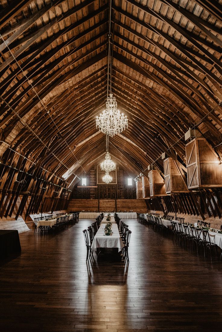 the inside of a barn with tables and chandeliers