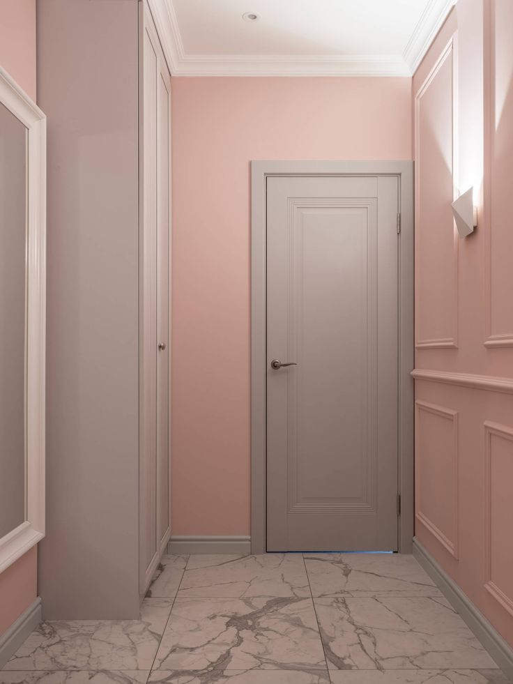 an empty hallway with pink walls and white trim on the doors is pictured in this image