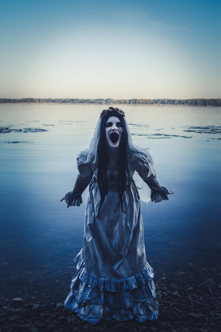 a creepy woman standing in the water with her mouth open