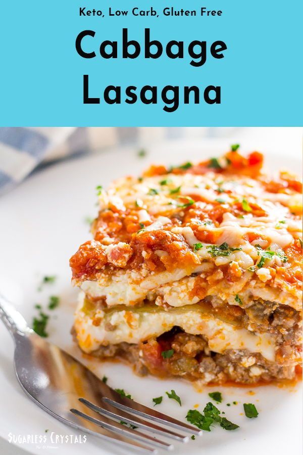 a white plate topped with lasagna covered in cheese and sauce next to a fork