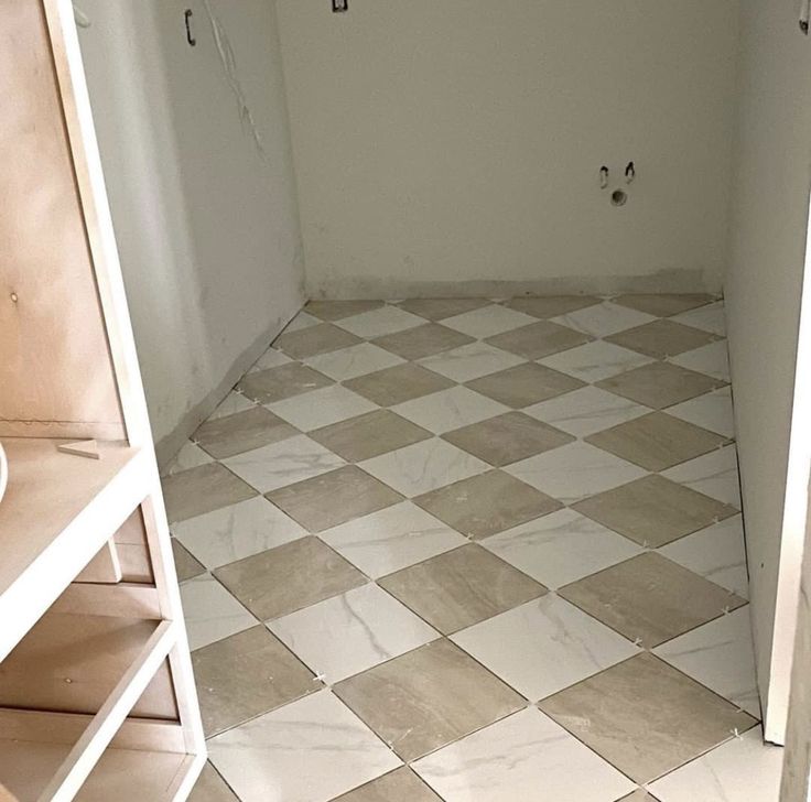 a white and brown checkered floor in a bathroom next to a shelf filled with toilet paper