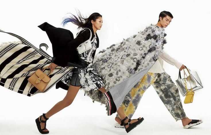 two women walking down the runway carrying bags