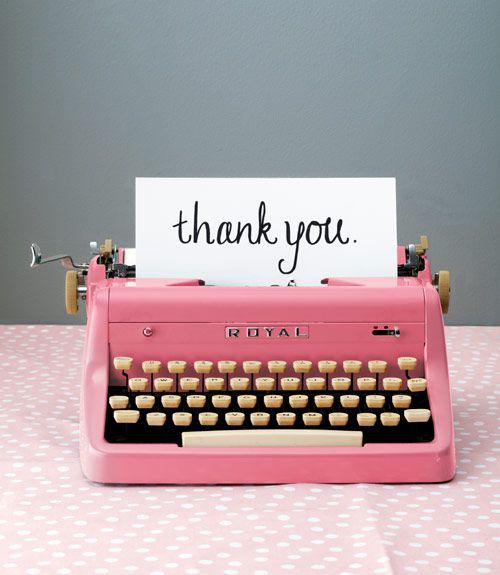 a pink typewriter sitting on top of a table with a thank you sign above it