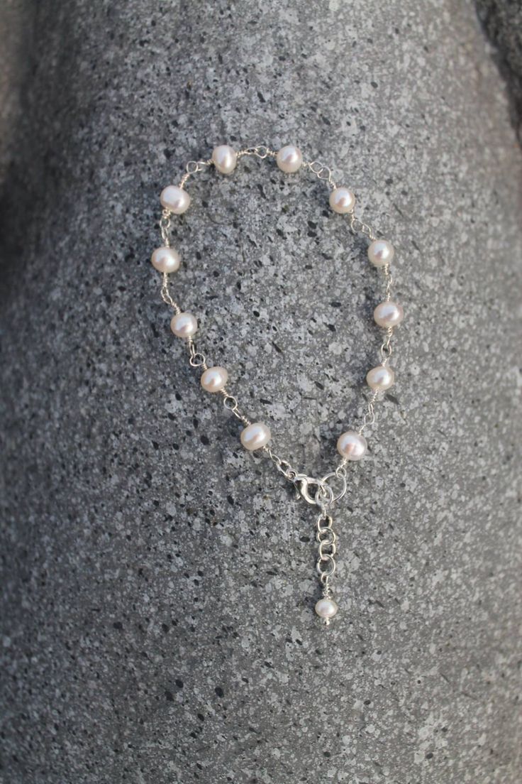 a close up of a bracelet with pearls and a cross on the end of it