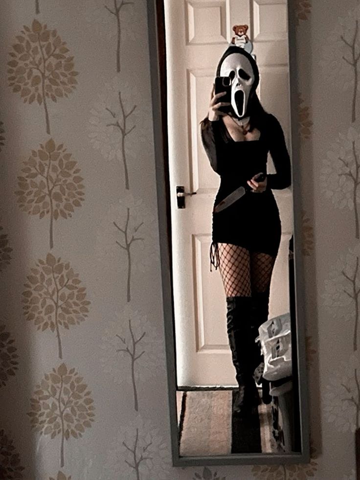 a woman wearing a mask is taking a selfie in the mirror