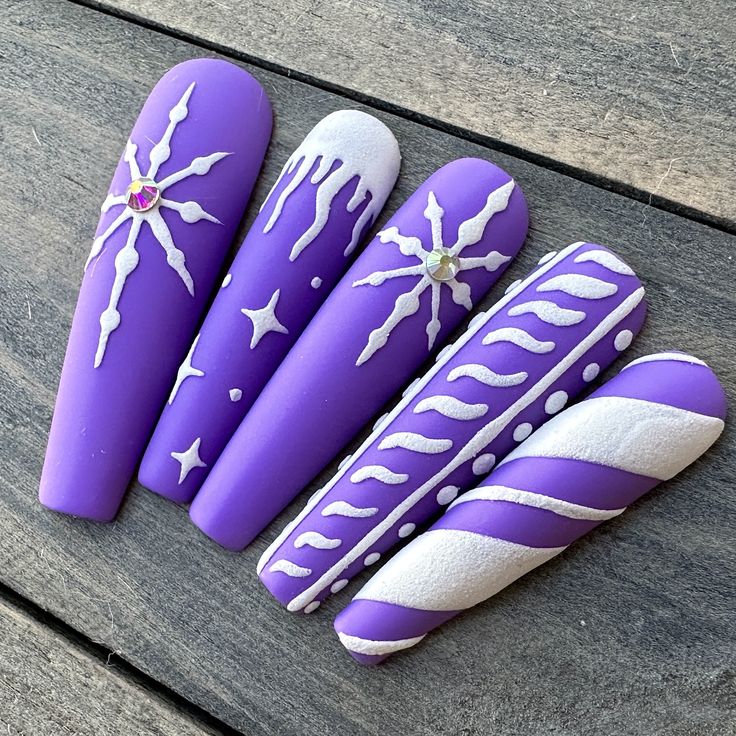 Dawn Witch Designs Unique, re-usable, hand painted, and made in Canada. These luxury press on nails are handmade using high quality gel polish and salon-grade materials.  ✨ PURPLE SNOWFALL ✨  Set on a matte purple background, this manicure features 3D icicles, snowflakes, and stripes. *The shape shown in the pictures is the LONG STILETTO *Colours may appear a little different due to your personal monitor settings* ✨ BUY 3 GET 1 PROMOTION ✨ ➜ Buy 3 sets of press on nails and get 1 set free! (Free Purple Christmas Nails Acrylic, Purple Xmas Nails, Christmas Purple Nails, Nail Art Designs For Winter Purple, Winter Nails Purple, Purple Winter Nail Designs, Christmas Nails Purple, Purple Snowflake Nails, Purple Christmas Nail Designs