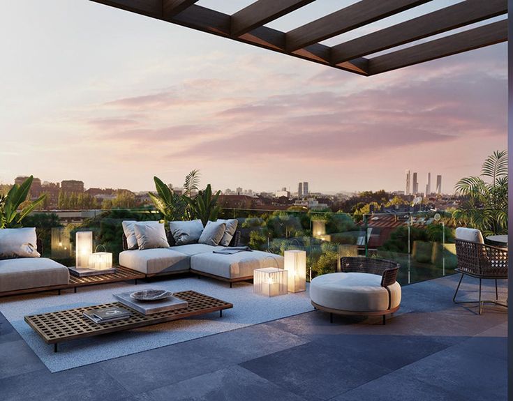 an outdoor living area with couches, tables and lamps on the roof terrace at sunset