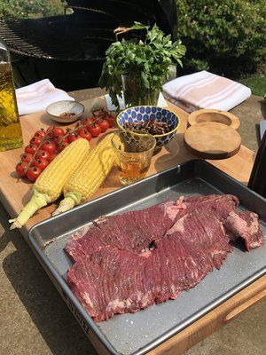 an outdoor grill with meat and vegetables on it, along with other ingredients for cooking