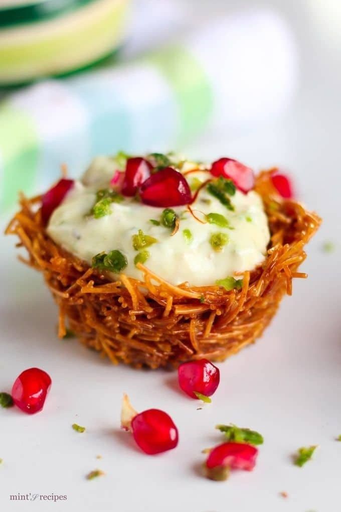 some food is sitting on a white plate with pomegranates around it