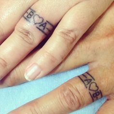 two people with tattoos on their fingers and one has a name tattooed on the middle finger