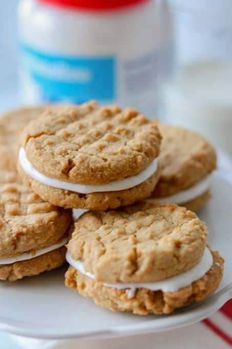 cookies with white frosting on a plate next to a bottle of milk