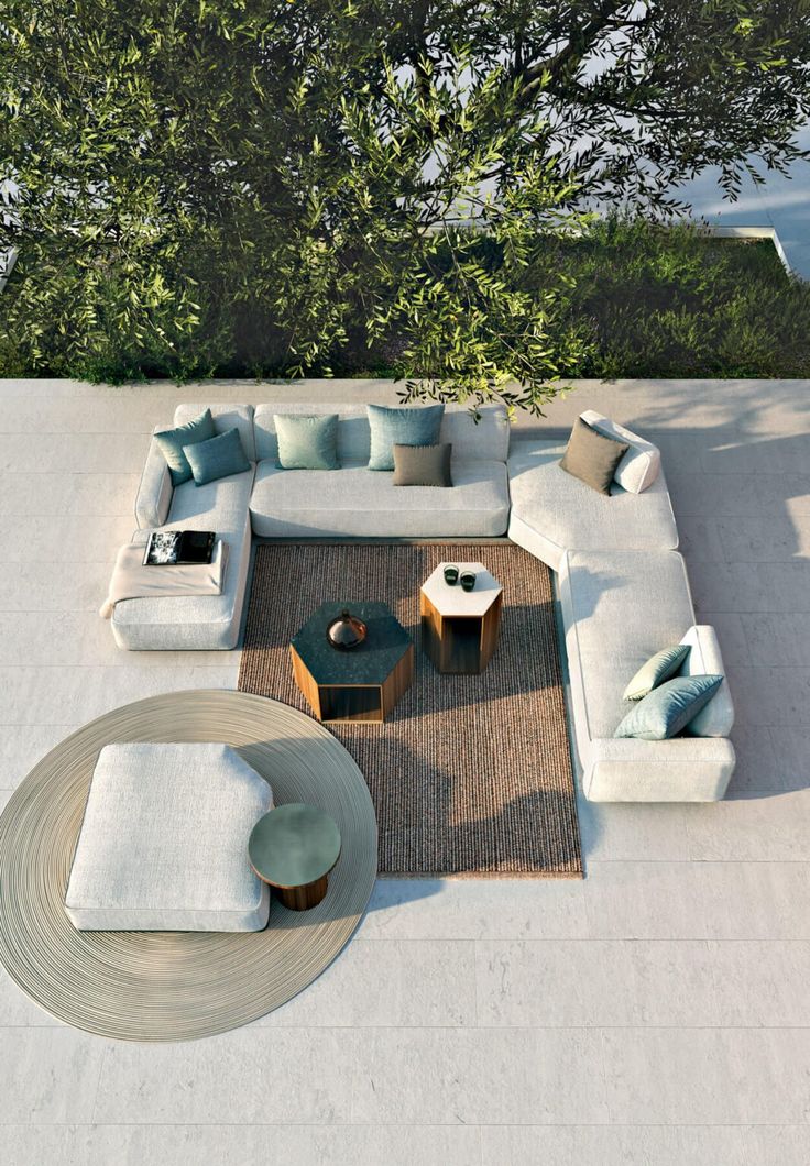 an aerial view of a living room with couches, tables and trees in the background