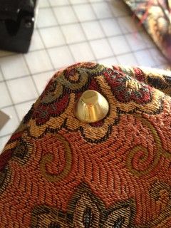 an orange and gold purse sitting on top of a tiled floor next to a toilet