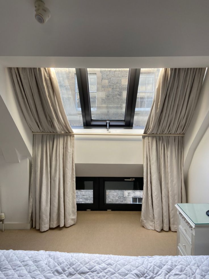 a bedroom with a large window and white bedding