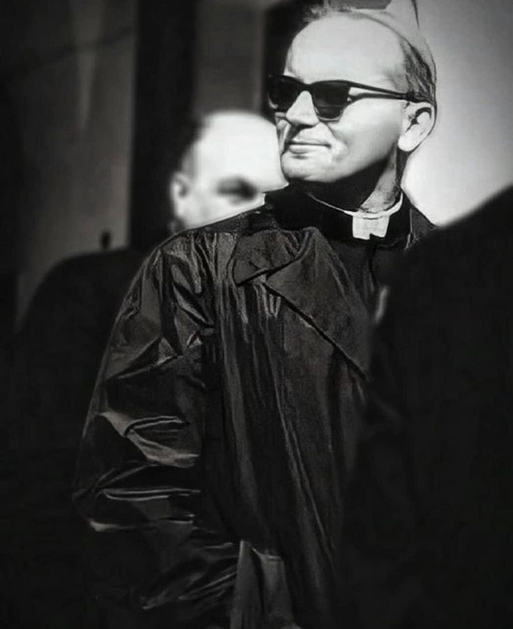 a man wearing sunglasses and a black leather jacket is standing in front of other men