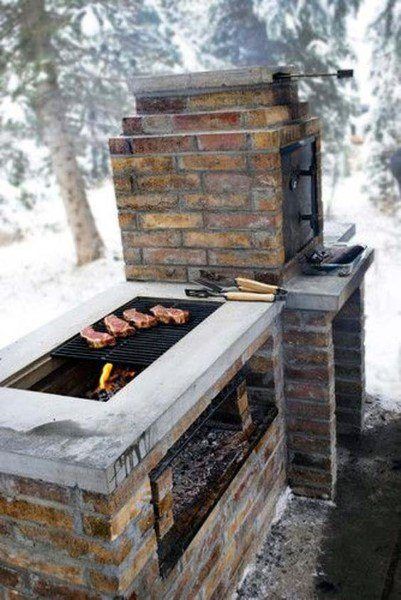 an outdoor bbq grill in the snow with food cooking on it's side