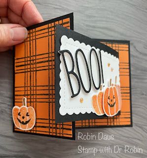 a hand holding up a card with the word boo on it and two pumpkins