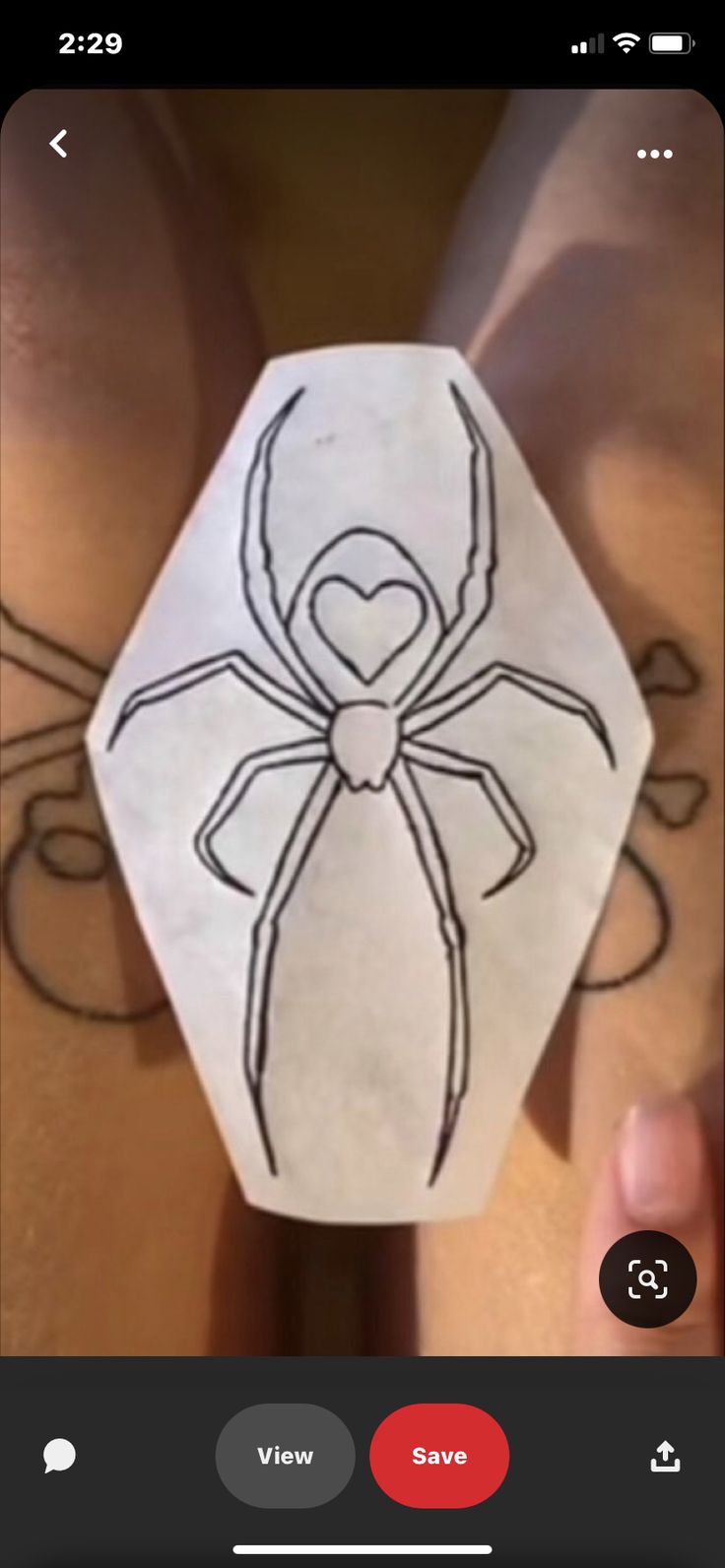 a person holding up a paper cut out with a spider on it's back