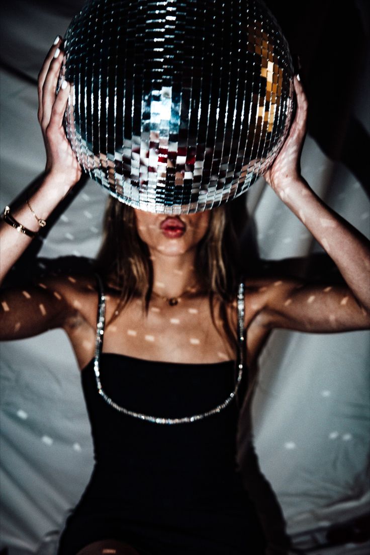 a woman holding a disco ball over her head