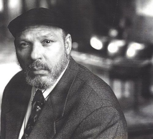 black and white photograph of a man with a beard wearing a suit, tie and hat