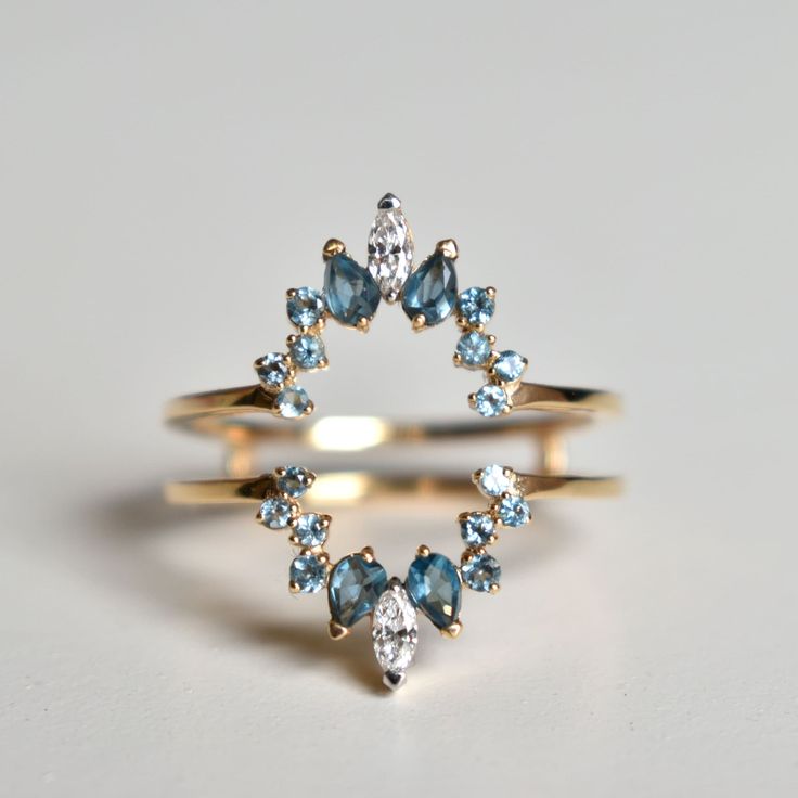 a gold ring with blue and white stones in the shape of a star, on a gray background