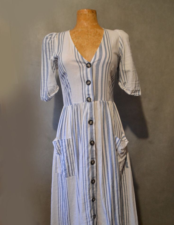 This cute dress can easily be dressed up or down.  It not only has 10 adorable buttons down the front but it has pockets as well.   Bust= 30in Waist= 28in (stretches) Shoulder to hem= 42in Sleeve= 12in Cute Button-up Spring Dresses, Casual Beach Dress With Button Cuffs, Cute Button-up Summer Dresses, Cute Summer Button-up Dresses, Cute Spring Button-up Dress, Cotton Button-up Sundress, Fitted Button-up Midi Dress With Pockets, Cute Button-up Cotton Dresses, Cotton Button-up Dress For Day Out