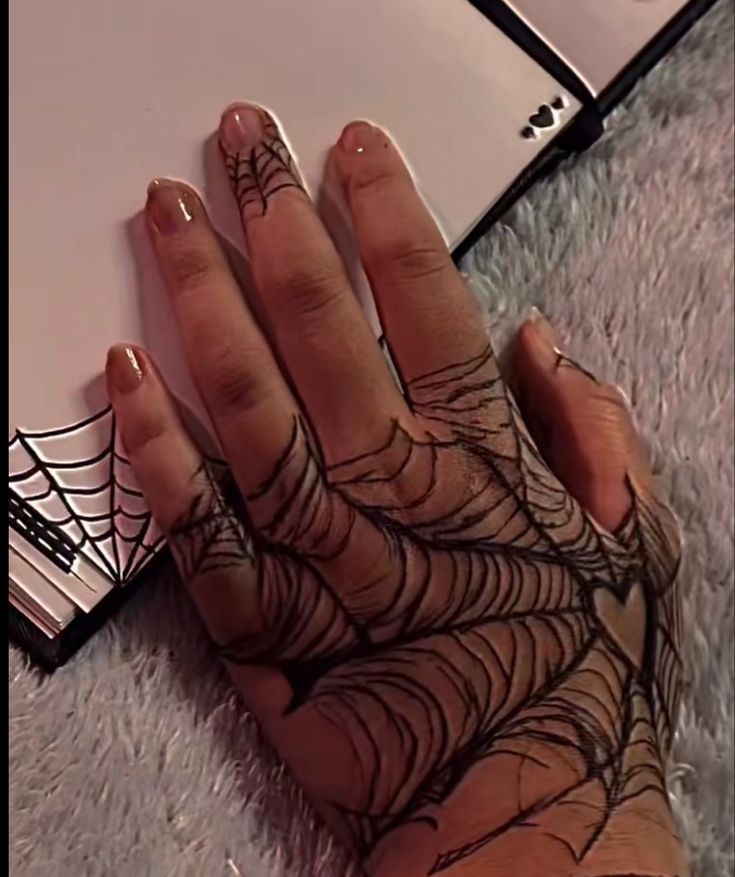 a woman's hand with spider web on it and her nails in the shape of a laptop