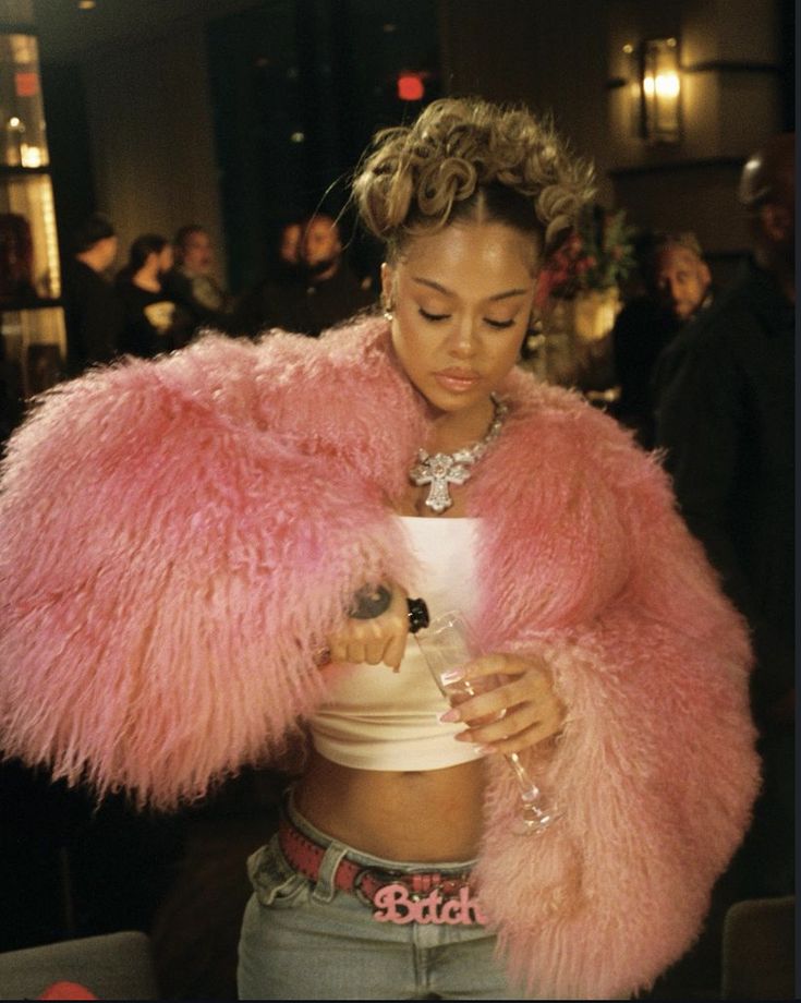 a woman in a pink fur coat looking at her cell phone