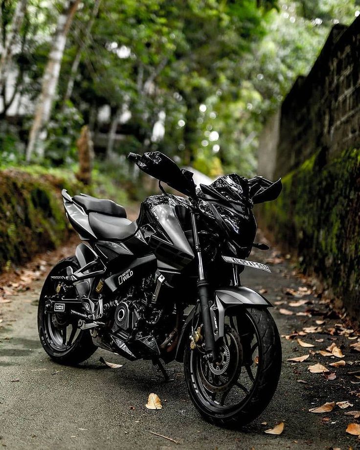 a black motorcycle parked on the side of a road in front of trees and bushes