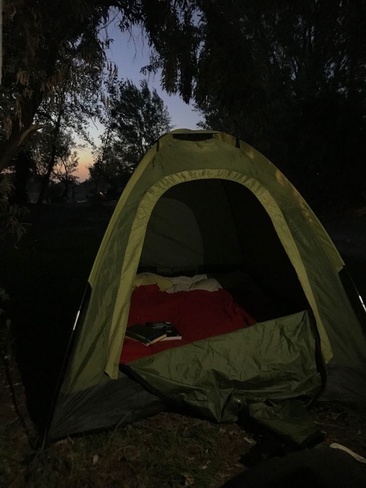 a tent is set up in the grass at night with its lights on and it's door open