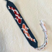 a piece of beaded fabric with an orange and white design on it, next to a string