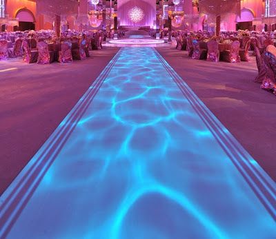 an indoor event venue with blue lighting and long tables set up for a formal function