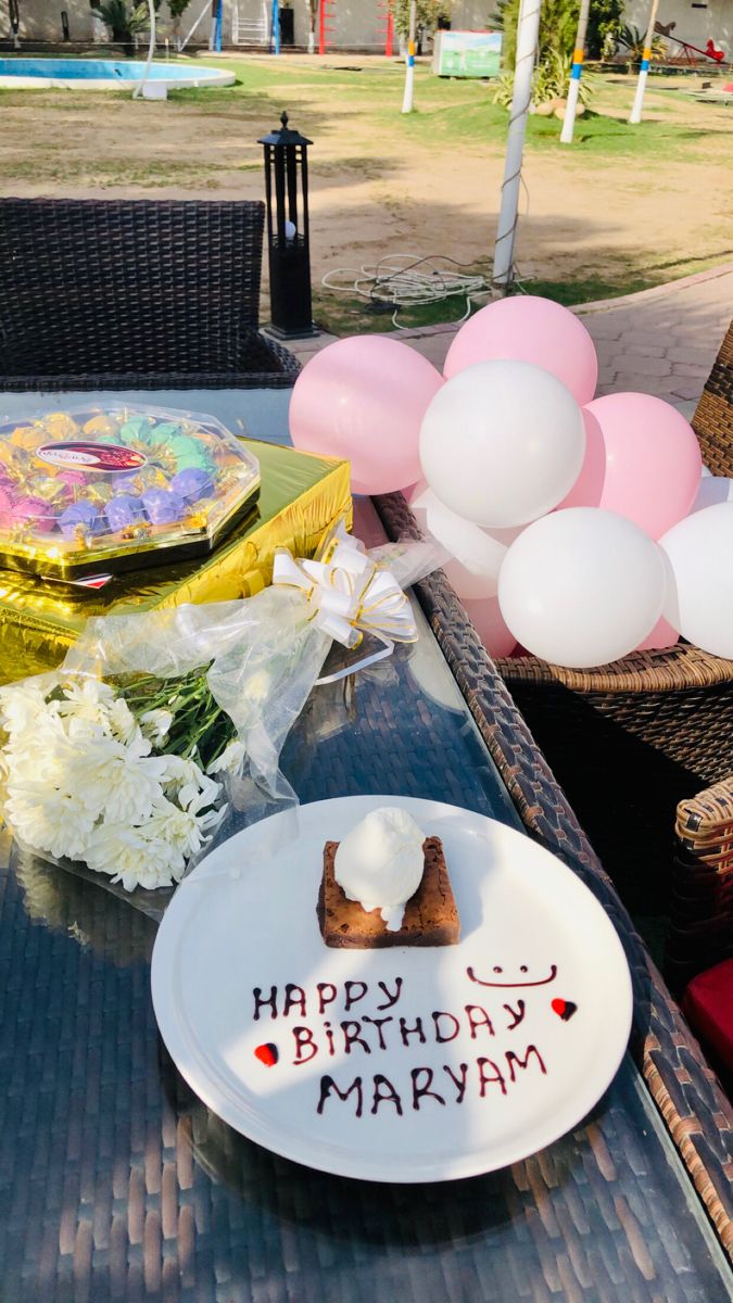 a birthday cake on a plate with balloons in the background