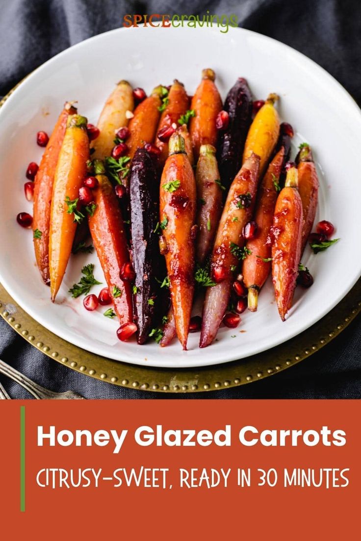 honey glazed carrots on a white plate with pomegranate and parsley