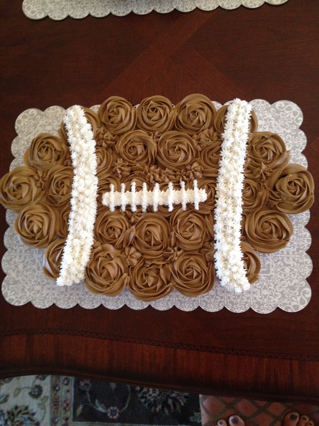 a cake made to look like a football with roses on the side and lace around it