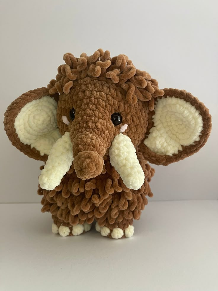 an elephant stuffed animal with white tusks and brown ears sitting on a table