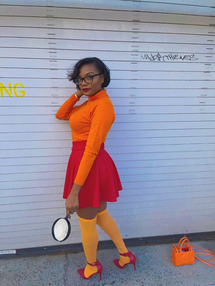 a woman in an orange top and red skirt is holding a white frisbee