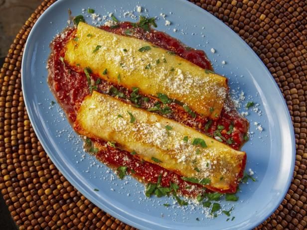 two enchiladas on a blue plate topped with parmesan cheese and red sauce