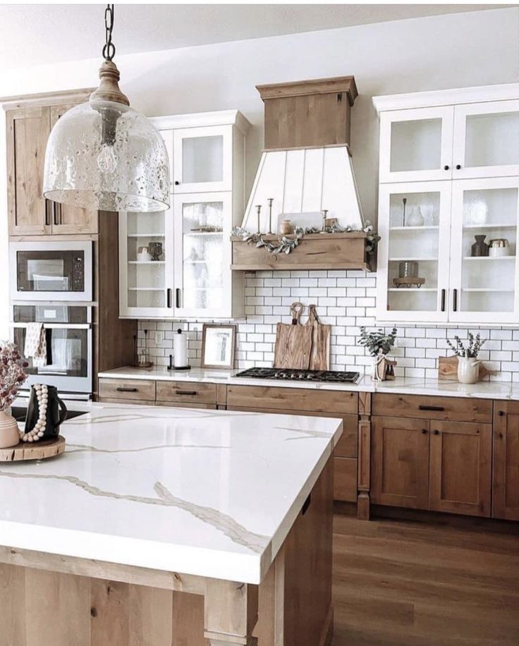 a kitchen with white marble counter tops and wooden cabinets, an island in the middle