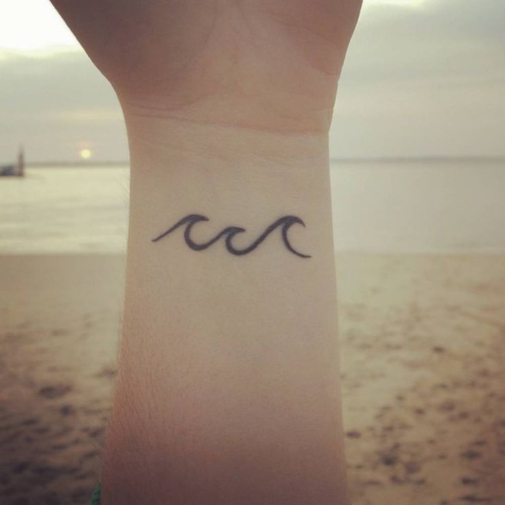 a woman's wrist with the word love written on it and an ocean in the background