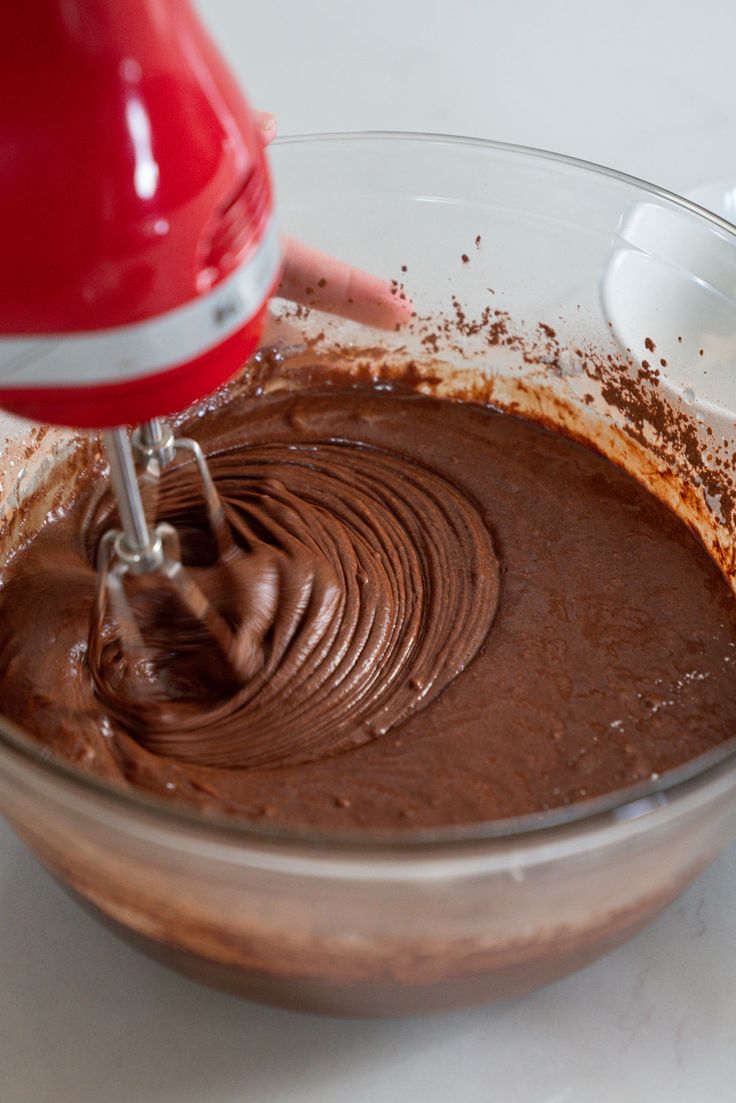 someone mixing chocolate in a bowl with a mixer