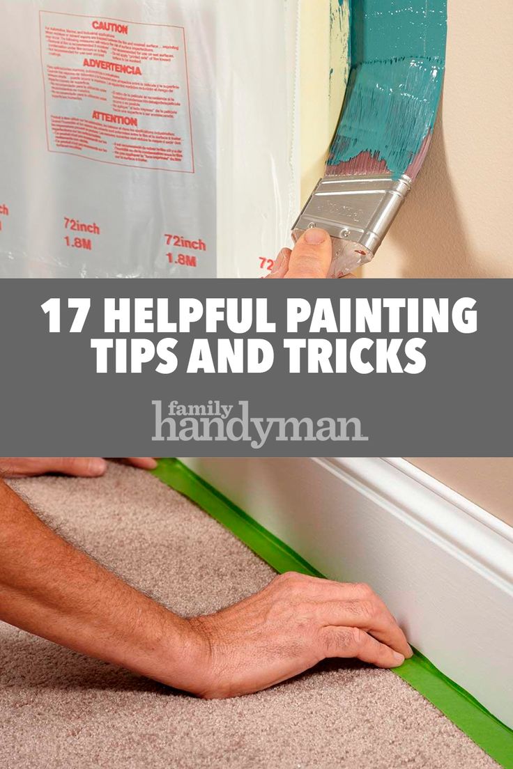 a man is painting the wall with green tape and white paint, while holding a brush in his hand