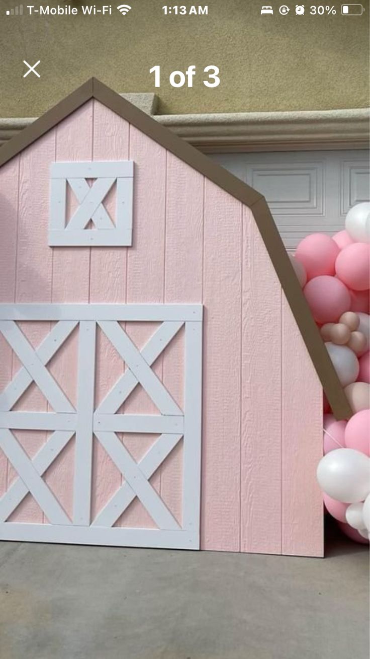 a pink barn with balloons in front of it