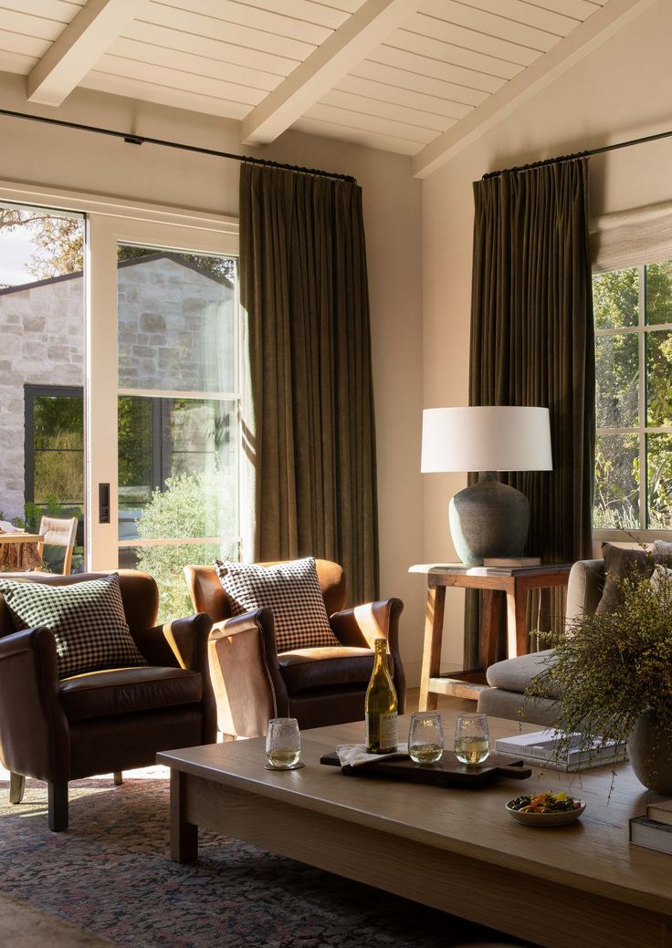 a living room with couches, chairs and a table in front of large windows