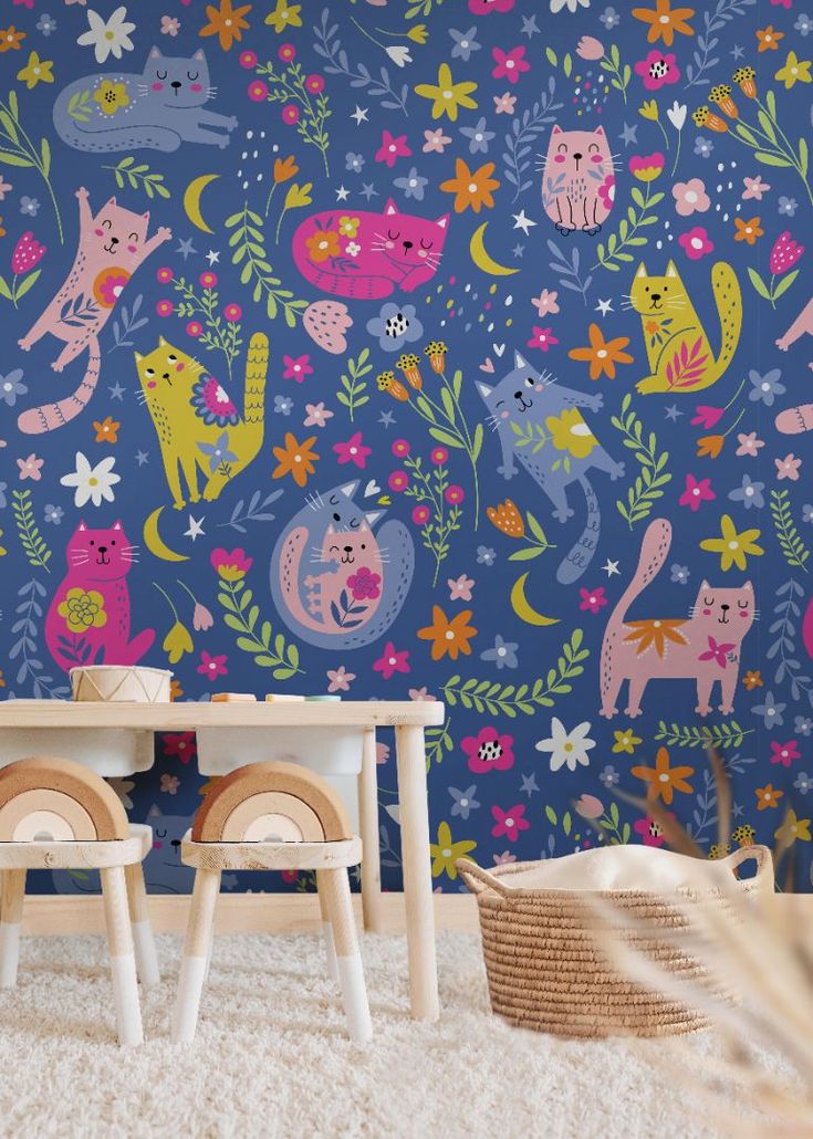 two children's chairs and table in front of a blue wall with colorful cats on it