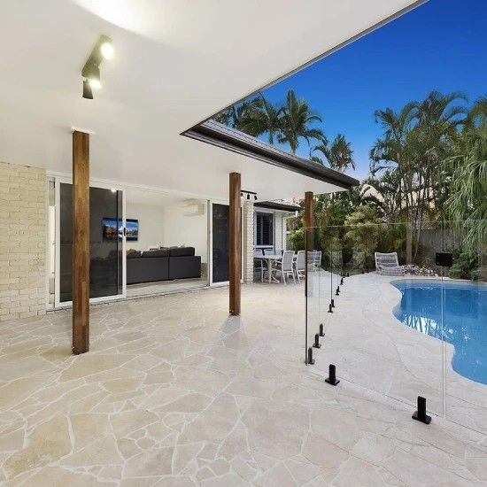 an indoor swimming pool in the middle of a large backyard with palm trees and chairs