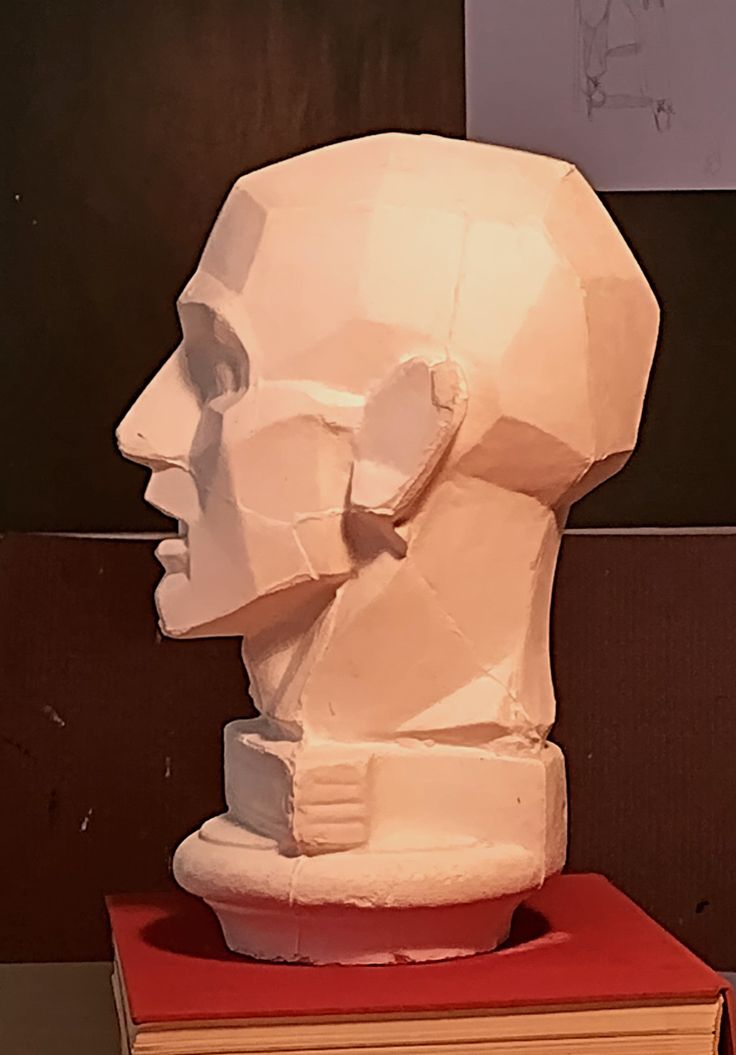 a sculpture of a man's head sitting on top of a stack of books